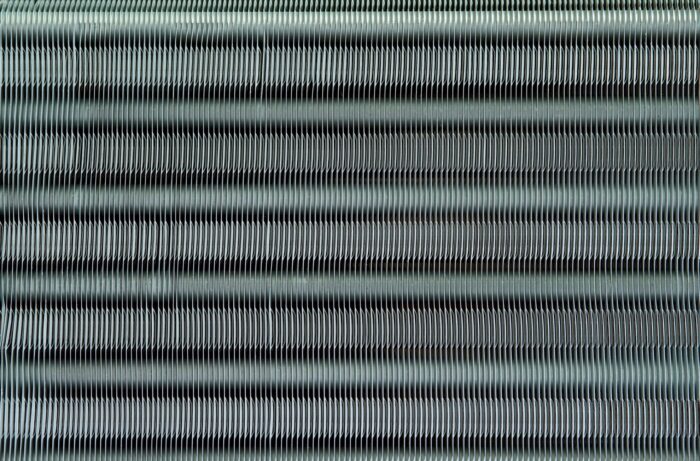 Photo of coil fins illustrates blog: "Why Is It Important to Fix Bent Coil Fins? Bent condenser coil fins may seem like small potatoes compared to other AC problems. However, while it’s true that this is a relatively simple task, that doesn’t mean that you should overlook it. Keep reading to learn more. Why Is It Important to Fix Bent Coil Fins? As you may have noticed, it’s not uncommon for the fins on your condenser coil to get bent over time. This is more than a cosmetic issue, as bent fins can impact the performance of your HVAC unit. Coil fins are really thin, so they can bend at the slightest contact, like hail, sleet, or pressure washing for example. Needless to say, you can also bend your coil fins while cleaning your coils or changing a filter. Coil fins play an important role in the heat transfer process that keeps your home cool. Bent coil fins increase heat retention, hindering the efficiency of your unit How To Fix Bent Condenser Coil Fins Straightening bent condenser coil fins is relatively easy but you should consider doing it yourself only if you feel 100% confident performing the tasks outlined below. If you don’t feel comfortable carrying out these steps, or just don’t have the time, don’t worry — you can always contact our experts at Zero Heating AC and Refrigeration, and they’ll take care of it. The first thing to do is to have the right tool, so make sure to purchase a coil fin comb. They usually come with several interchangeable heads, so you don’t have to worry about buying a specific type of comb. Turn off the power to your air conditioner Remove the panel and grille to expose the fins Remove screws and lift off the fan and grille Take off the plate to the evaporator coil Use the appropriate fin comb head and start straightening from the bottom I Zero Heating AC and Refrigeration: the Best In San Antonio, TX Whether you need to repair or replace your AC unit, Zero Heating AC and refrigeration and Refrigeration is your best option in San Antonio, Texas. Contact us today using our website, by telephone (210-900-0824), or through our social media accounts on Facebook and Twitter and to schedule a tune-up or to get a free estimate. We also offer financing plans for your convenience."