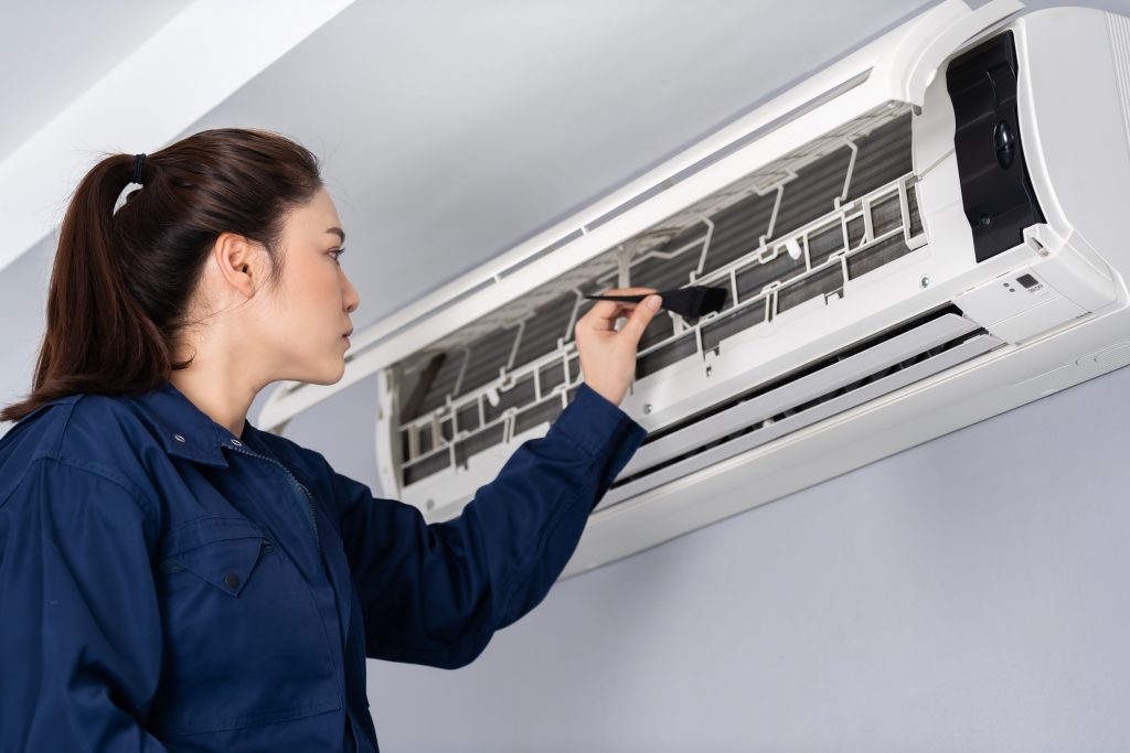 Image of woman inspecting AC unit illustrates blog: "4 AC Tips for This Labor Day Weekend"