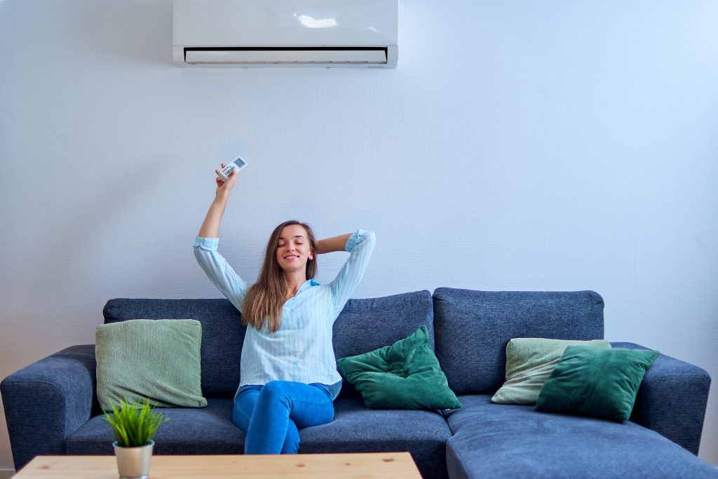 Photo of woman with AC remote control illustrates blog "4 Air Conditioning New Year’s Resolutions for 2022"