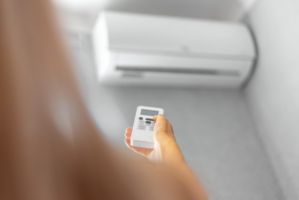 Image of woman and air conditioning unit illustrates blog: Spring Maintenance Tips for Your AC