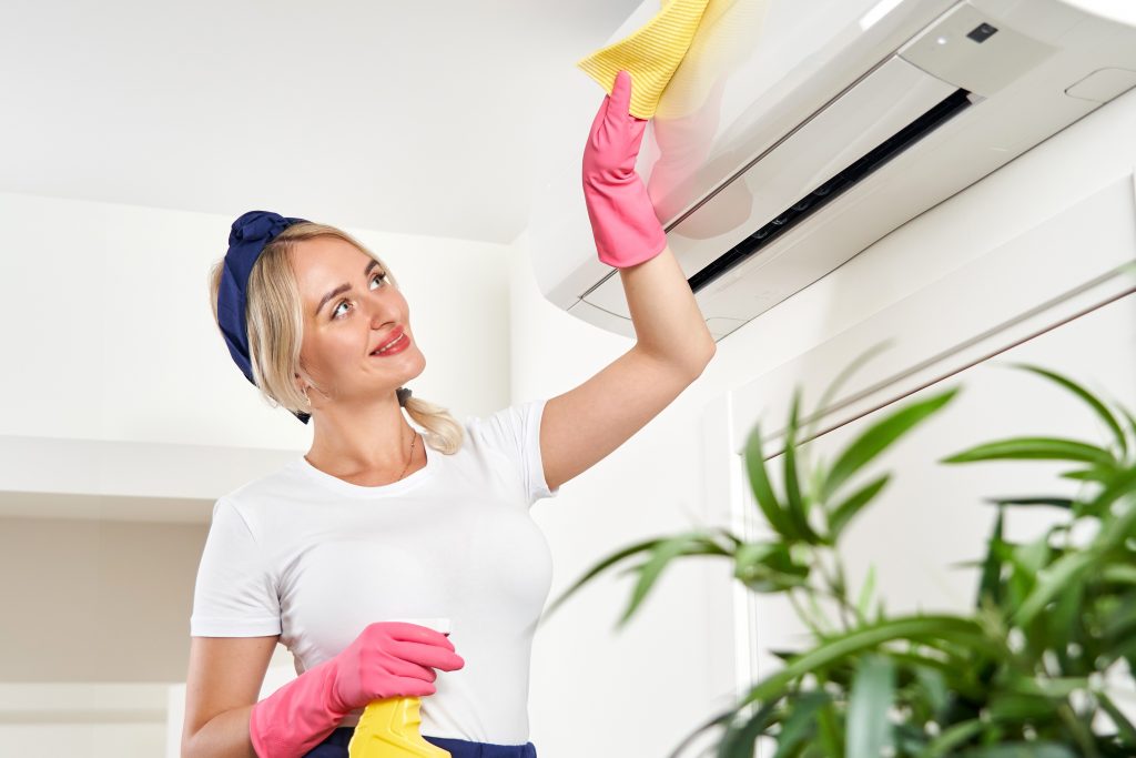 Photo of woman cleaning air conditioning illustrates blog: 4 Ways to Show Your AC Some Love This Valentine’s Day