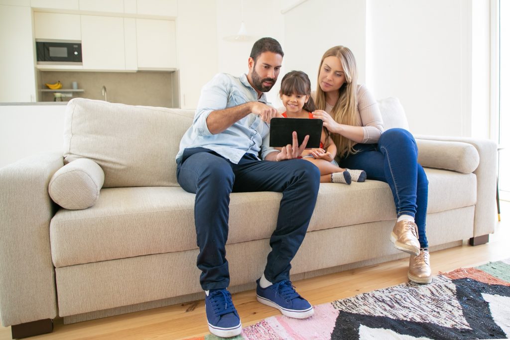 Photo of family in living room looking at tablet illustrates blog: "Can Your HVAC Filters Help You Contain COVID?"