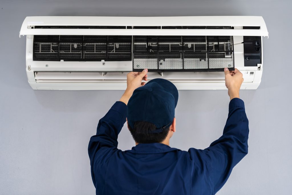 Photo of technician fixing air conditioning illustrates blog: "Can I Repair My Air Conditioning Myself?"