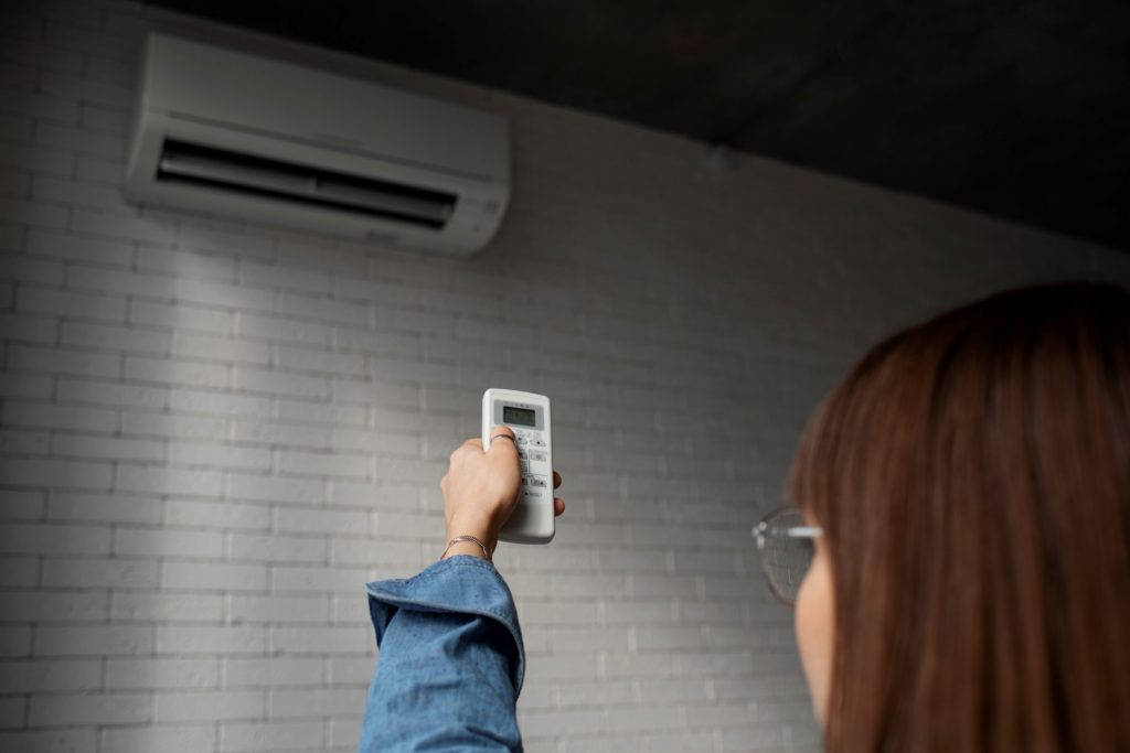 Woman pointing AC remote at AC unit