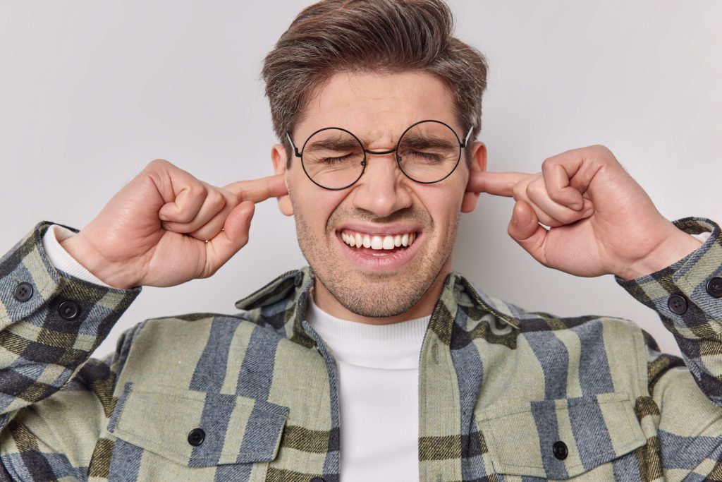 Photo of man with glasses covering his ears.