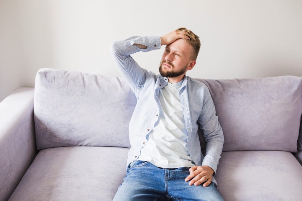 Man looking uncomfortable in couch illustrates blog "Why Is My AC Fan Not Working?"