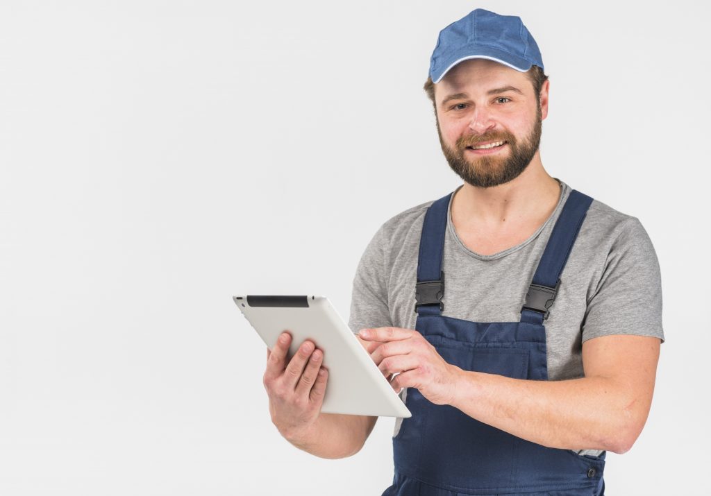 Handyman holding tablet illustrates blog "Why Is My AC Fan Spinning Backwards?"