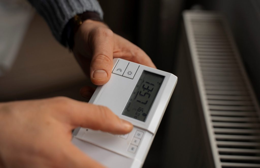 Closeup of man holding thermostat illustrates blog "Are AC Thermostats Universal?"